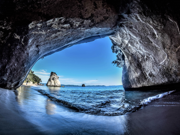 Coastal rock arch opening onto turquoise water in New Zealand