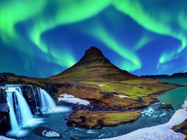 Northern lights over an Icelandic mountain and waterfall
